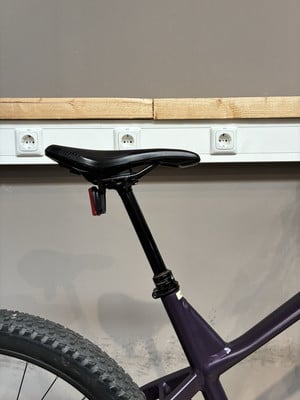 Eine schwarze Sattelstütze mit rotem Licht an einem Fahrrad vor einer Wand. Eine schwarze Sattelstütze mit rotem Licht an einem Fahrrad vor einer Wand.