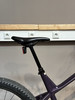 Eine schwarze Sattelstütze mit rotem Licht an einem Fahrrad vor einer Wand.