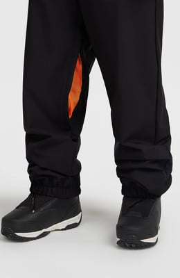 Schwarze Hose mit orangenem Detail und schwarzen Stiefeln im Schnee. Schwarze Hose mit orangenem Detail und schwarzen Stiefeln im Schnee.