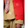 Detail eines Outfits mit rotem Cardigan, Krawatte und beiger Jacke.