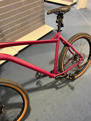 Ein rotes Mountainbike mit braunen Reifen steht auf einem blauen Teppich. Ein rotes Mountainbike mit braunen Reifen steht auf einem blauen Teppich.
