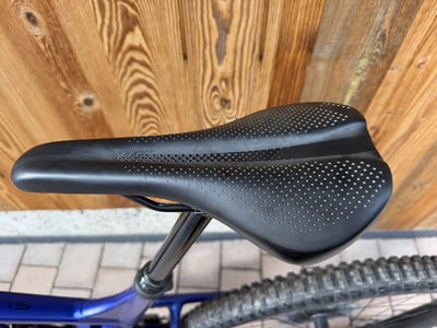 Schwarzer Fahrradsattel mit perforiertem Muster auf Holzuntergrund. Schwarzer Fahrradsattel mit perforiertem Muster auf Holzuntergrund.