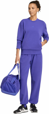 Eine Frau in violetter Kleidung hält eine blaue Tasche und trägt schwarze Schuhe. Eine Frau in violetter Kleidung hält eine blaue Tasche und trägt schwarze Schuhe.