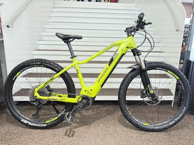 Ein grünes Genesis E-Bike mit Federung und Scheibenbremsen steht auf einer Treppe. Ein grünes Genesis E-Bike mit Federung und Scheibenbremsen steht auf einer Treppe.