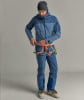 Ein Mann in einer blauen Jacke und Hose mit Klettergurt schließt eine Schnalle.