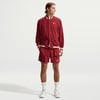 Ein Mann in roter Nike-Kleidung mit Logo auf Jacke und Shorts.