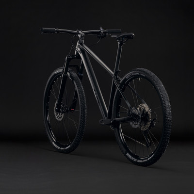 Schwarzes Mountainbike mit mattem Rahmen und schwarzen Rädern vor dunklem Hintergrund.