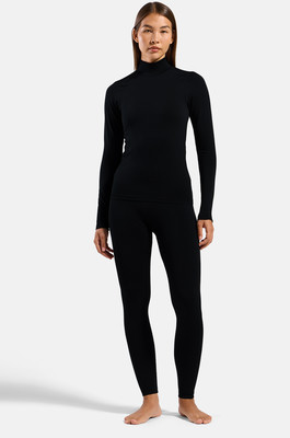 Eine Frau in einem schwarzen Rollkragenpullover und Leggings steht auf weißem Hintergrund. Eine Frau in einem schwarzen Rollkragenpullover und Leggings steht auf weißem Hintergrund.