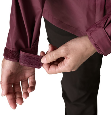 Eine Hand schließt den Klettverschluss am Ärmel einer weinroten Jacke. Eine Hand schließt den Klettverschluss am Ärmel einer weinroten Jacke.