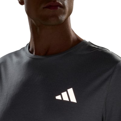 Ein Mann in einem grauen T-Shirt mit Adidas-Logo auf der Brust. Ein Mann in einem grauen T-Shirt mit Adidas-Logo auf der Brust.