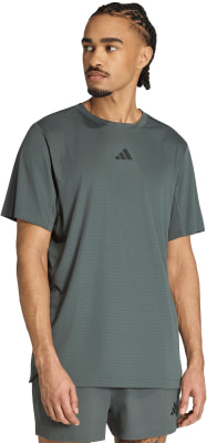 Ein Mann in einem dunkelgrünen Adidas T-Shirt mit kurzen Ärmeln und Shorts.