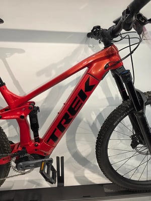 Ein rotes Trek Mountain-Elektrofahrrad mit silbernem Logo auf dem Rahmen. Ein rotes Trek Mountain-Elektrofahrrad mit silbernem Logo auf dem Rahmen.