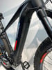 Detail des Rahmens eines schwarzen E-Bikes mit Logo und Pedalen.