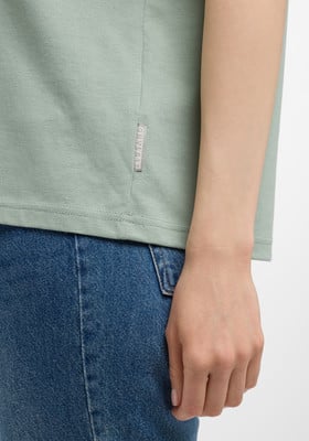 Details eines Damen-T-Shirts aus feinem Stoff und blauer Jeans.
