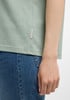 Details eines Damen-T-Shirts aus feinem Stoff und blauer Jeans.