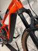 Detail eines orangefarbenen E-Bikes Vorderseite mit Federung und Reifen.