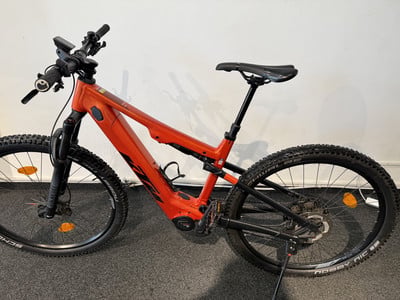 Orange E-Bike mit schwarzen Rädern und Sattel auf dunklem Untergrund. Orange E-Bike mit schwarzen Rädern und Sattel auf dunklem Untergrund.