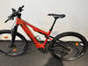 Orange E-Bike mit schwarzen Rädern und Sattel auf dunklem Untergrund.