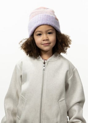 Mädchen mit lockigem Haar und lila Mütze vor weißem Hintergrund.