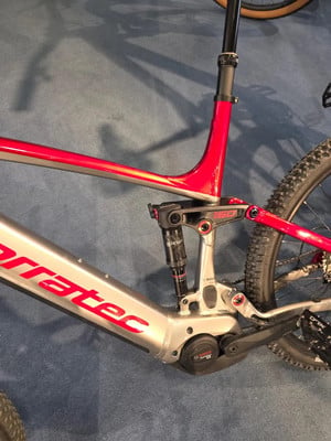 Detail eines Mountainbike-E-Bikes mit rotem Rahmen und Dämpfer.