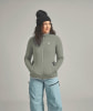 Eine Frau in einer grauen Jacke und hellblauen Skihose mit schwarzer Mütze.
