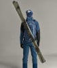 Ein Mann in blauer Jacke und Hose mit Skiern auf dem Rücken.