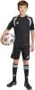 Junge in schwarzem Fußballtrikot mit weißen Streifen hält Ball.
