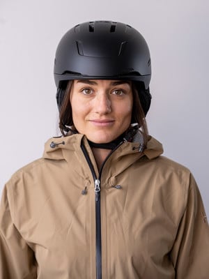 Eine Frau in einem Skihelm und einer Jacke lächelt in die Kamera.