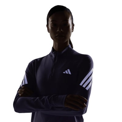 Nő sötét, hosszú ujjú pólóban Adidas logóval.