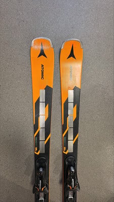 Atomic Redster Q9 Skier mit schwarzen und orangefarbenen Details auf grauem Hintergrund.