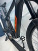 Schwarzes Mountain-Elektrofahrrad mit orangefarbenem Logo und Dämpfer.