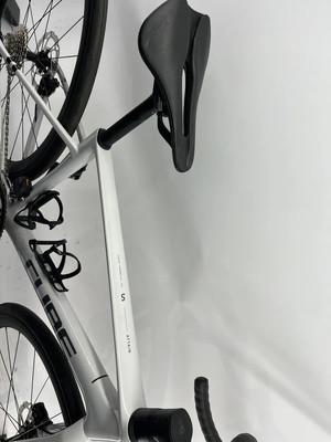 Ein Cube Attain Rennrad mit schwarzem Sattel hängt an einer weißen Wand. Ein Cube Attain Rennrad mit schwarzem Sattel hängt an einer weißen Wand.