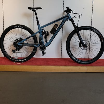 Ein blaues Fully-Mountainbike mit schwarzen Rädern und Dämpfer. Ein blaues Fully-Mountainbike mit schwarzen Rädern und Dämpfer.