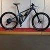 Ein blaues Fully-Mountainbike mit schwarzen Rädern und Dämpfer.