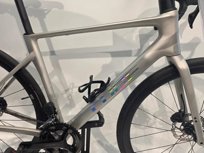 Silbernes Fahrrad mit holografischem Logo und schwarzen Rädern.