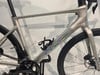 Silbernes Fahrrad mit holografischem Logo und schwarzen Rädern.