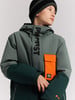 Junge in Winterjacke mit Kapuze und orangefarbener Brusttasche.