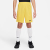 Ein Junge trägt eine gelbe Nike-Shorts und weiße Socken.