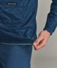 Detail einer Jacke mit ORTOVOX-Logo, Hand zieht Saum nach unten.