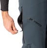 Eine Hand öffnet einen Reißverschluss an einer dunkelgrauen Hose mit Dynafit-Logo.