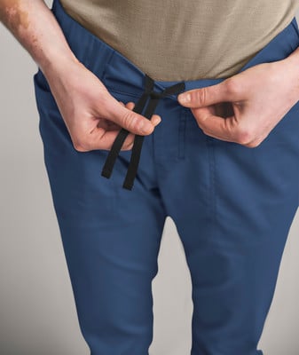 Eine Person bindet eine Kordel an blauen Hosen. Eine Person bindet eine Kordel an blauen Hosen.