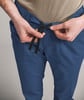 Eine Person bindet eine Kordel an blauen Hosen.