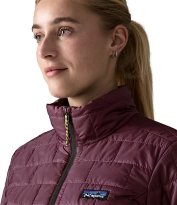 Eine Frau in einer dunkelweinvfarbenen Steppjacke mit Patagonia-Logo auf der Brust. Eine Frau in einer dunkelweinvfarbenen Steppjacke mit Patagonia-Logo auf der Brust.