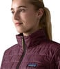 Eine Frau in einer dunkelweinvfarbenen Steppjacke mit Patagonia-Logo auf der Brust.