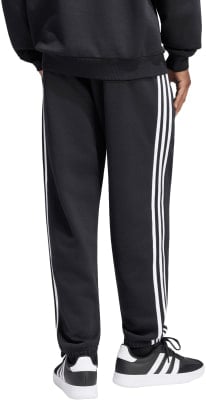 Schwarze Adidas Jogginghose mit weißen Streifen und weißen Sneakern.