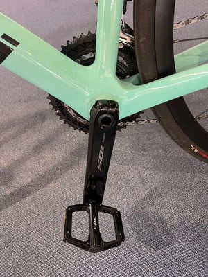 Detail einer Shimano 105 Fahrradkurbel mit Cytec-Pedal auf grauem Teppich. Detail einer Shimano 105 Fahrradkurbel mit Cytec-Pedal auf grauem Teppich.