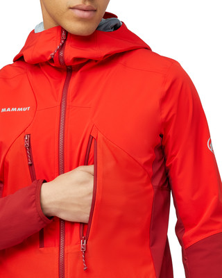 Ein Mann in einer roten Mammut-Jacke greift in die Seitentasche. Ein Mann in einer roten Mammut-Jacke greift in die Seitentasche.