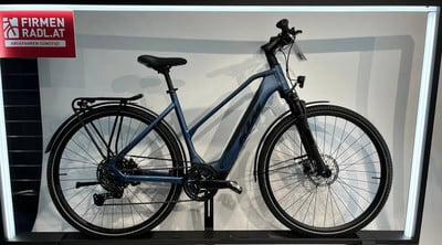 Blaues KTM E-Bike mit Gepäckträger und Schutzblechen vor weißem Hintergrund.