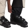 Eine Person passt eine schwarze Skihose über einen Skischuh an.
