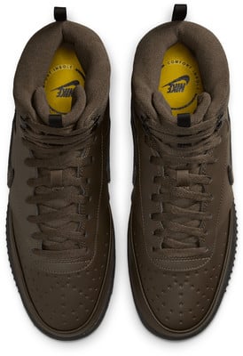 Draufsicht auf braune Nike-Sneaker mit reflektierendem Logo auf der gelben Einlegesohle. Draufsicht auf braune Nike-Sneaker mit reflektierendem Logo auf der gelben Einlegesohle.